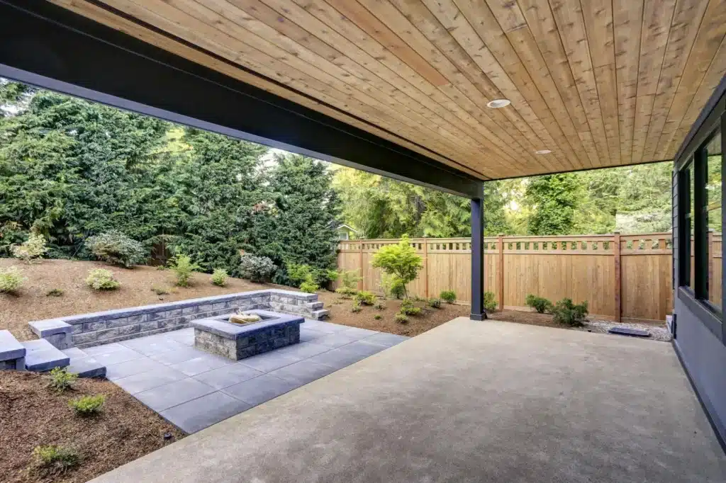 Covered outdoor patio with fire pit and custom hardscape landscaping in Southern Oregon