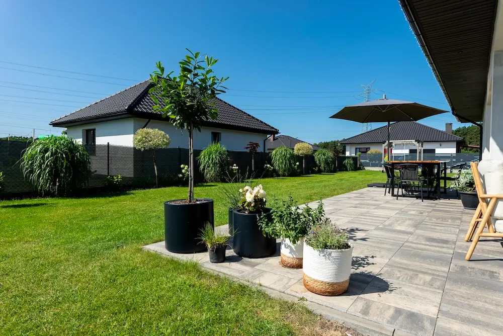 Private backyard concrete patio with outdoor seating, fire pit, wood privacy fence, and surrounding landscaping.