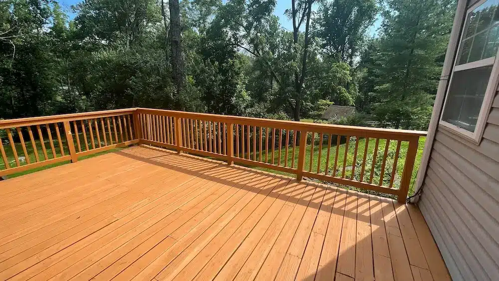 Spacious elevated wood deck with outdoor dining area overlooking a tree-filled landscape, ideal for a Brookings, Oregon coastal property.